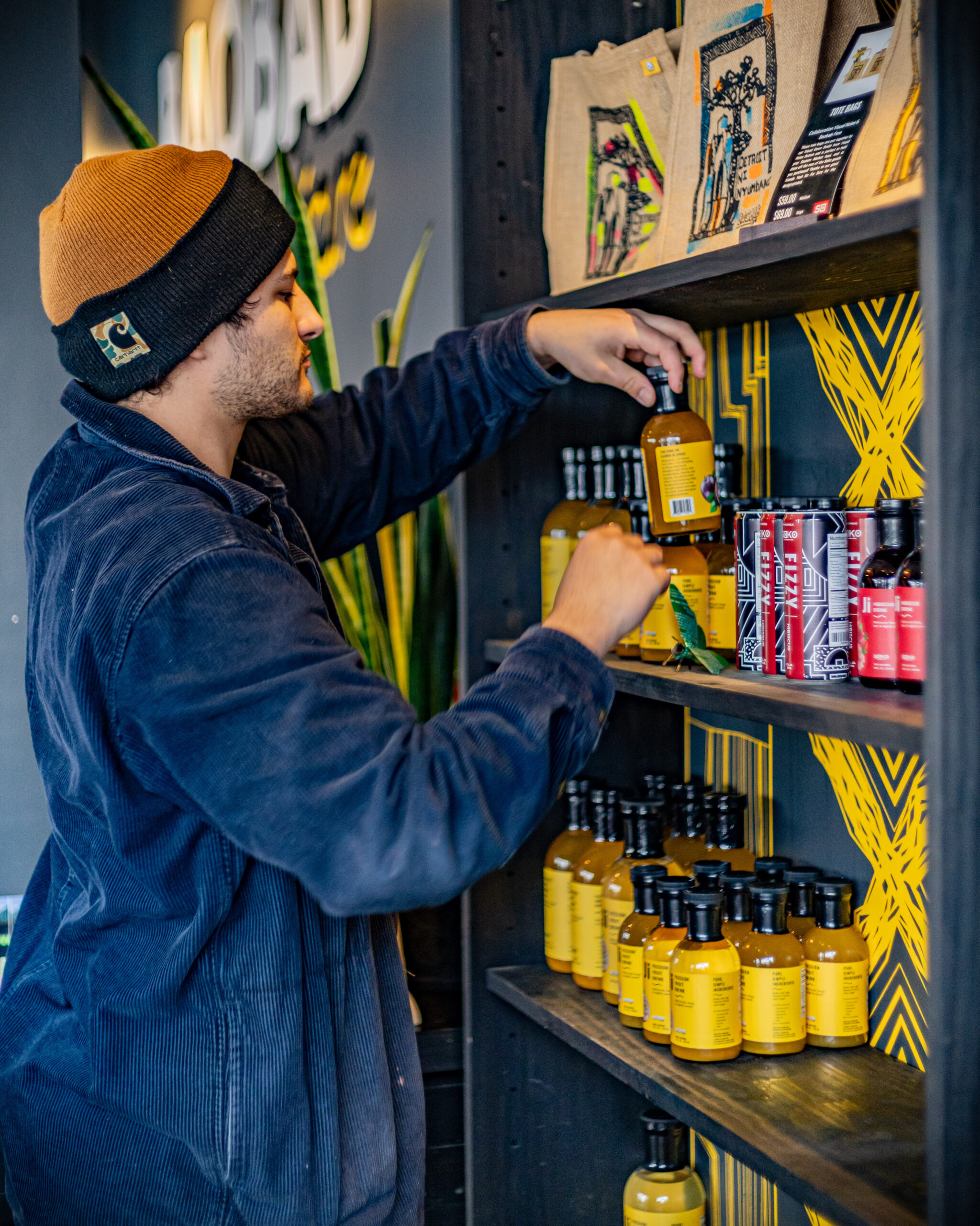 A young man grabs a bottle of Ji Passion Fruit from the retail shelves at Baobab Fare in Detroit