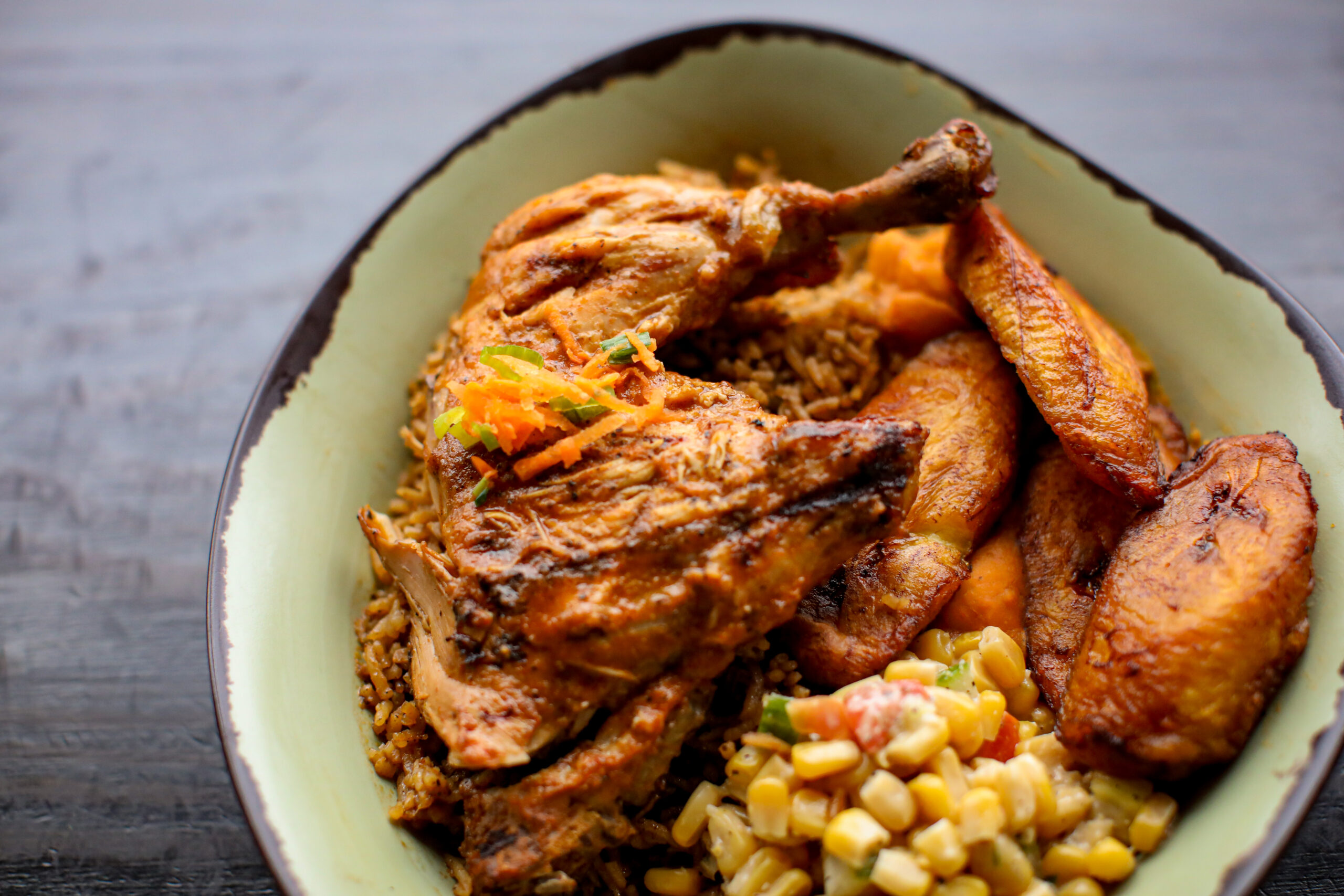 A plate of grilled chicken, plantains, rice, beans, and corn salad from Baobab Fare